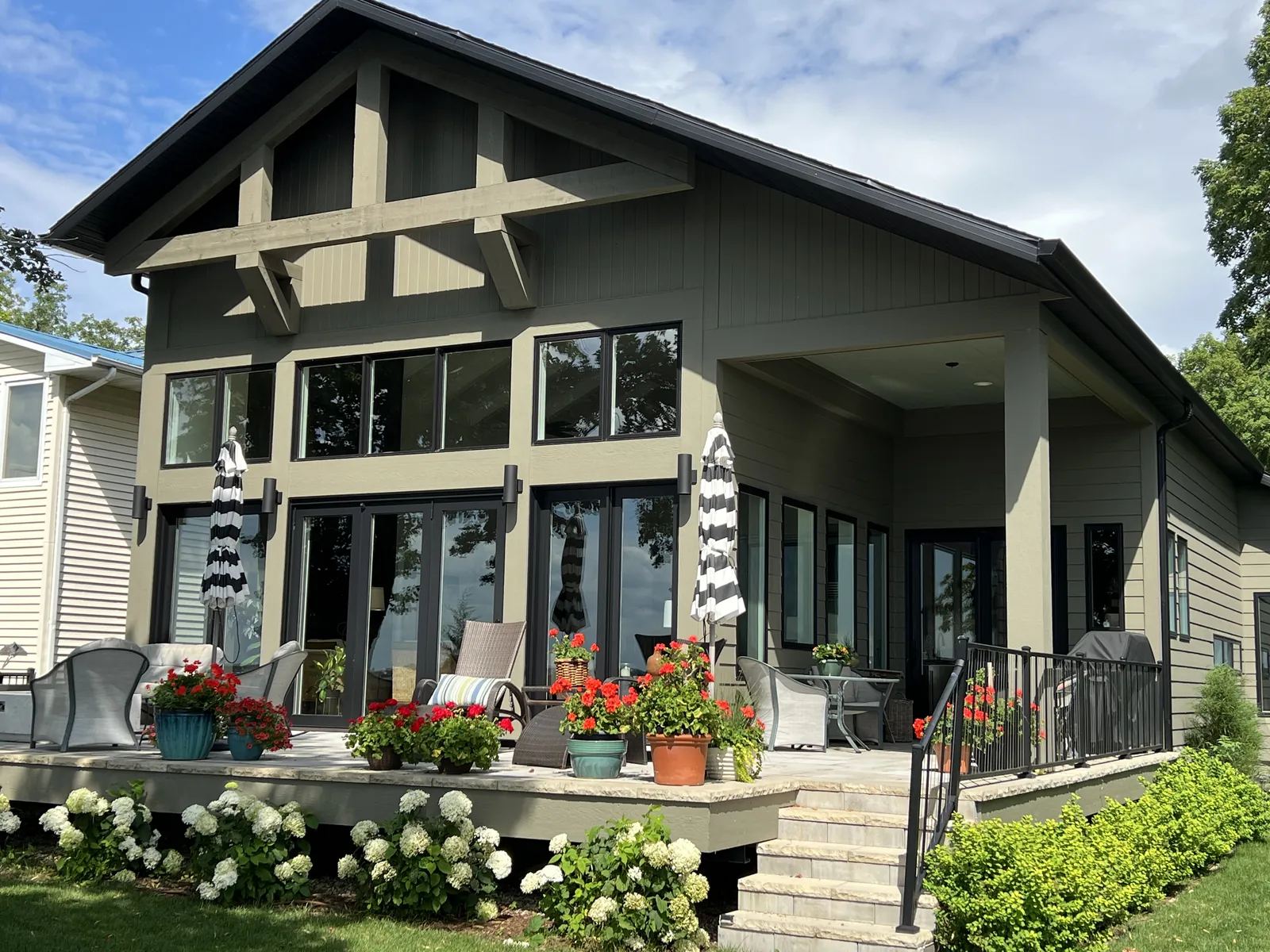 Craftsman-style lake home with tall windows and a flower-lined patio on West Lake Okoboji, Iowa
