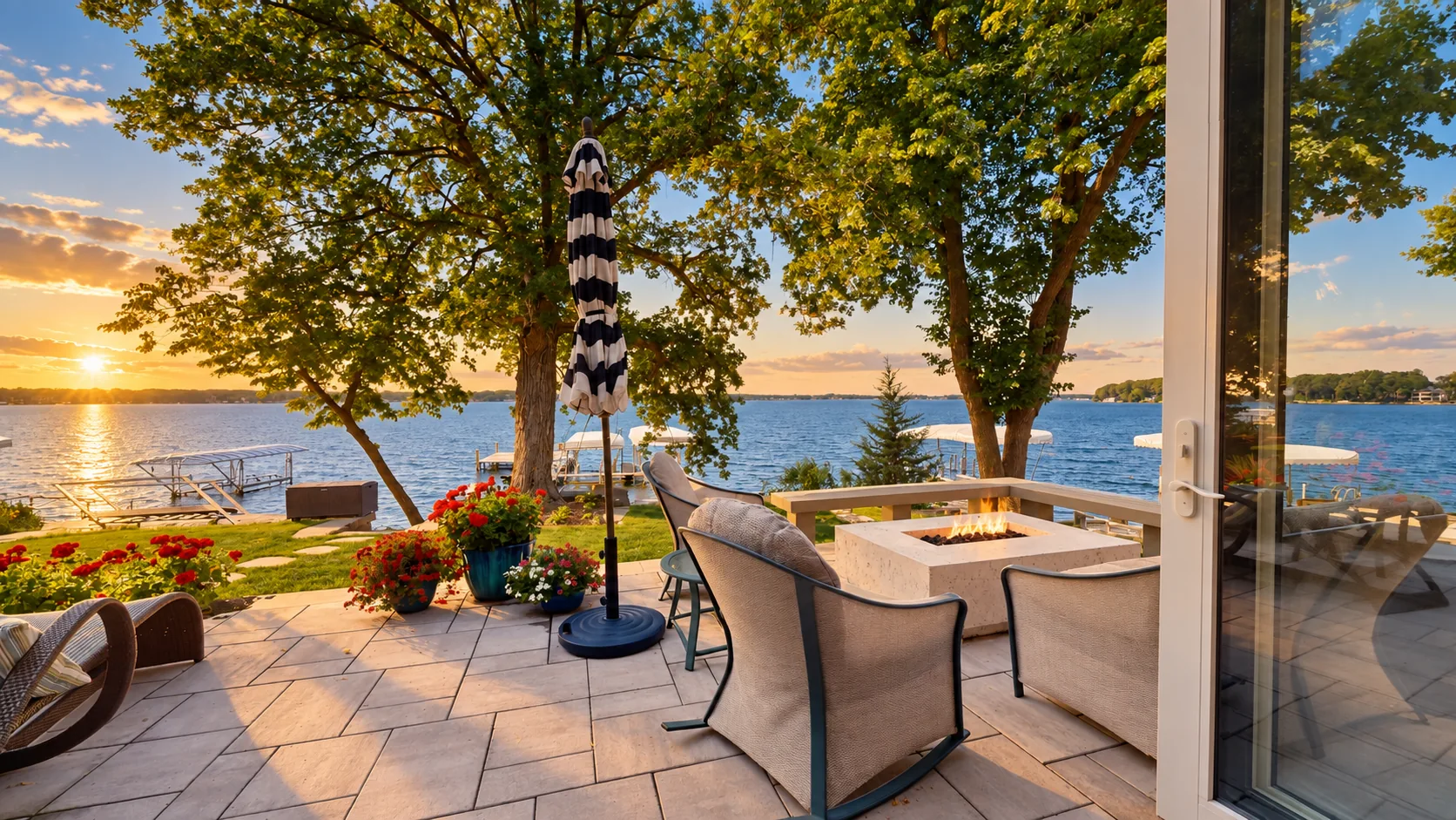 Golden-hour luxury lakefront patio with a fire table overlooking West Lake Okoboji, Iowa