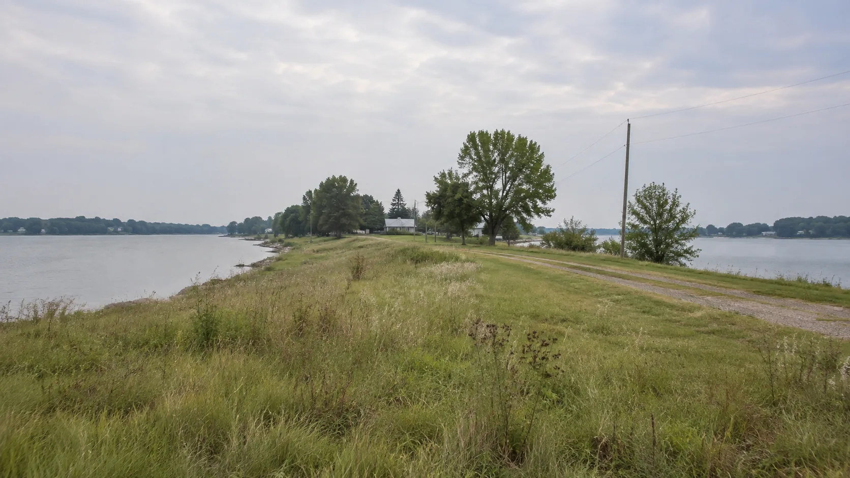 A gravel track along a narrow neck of land with lake water on both sides near Orleans, Iowa on a hazy morning